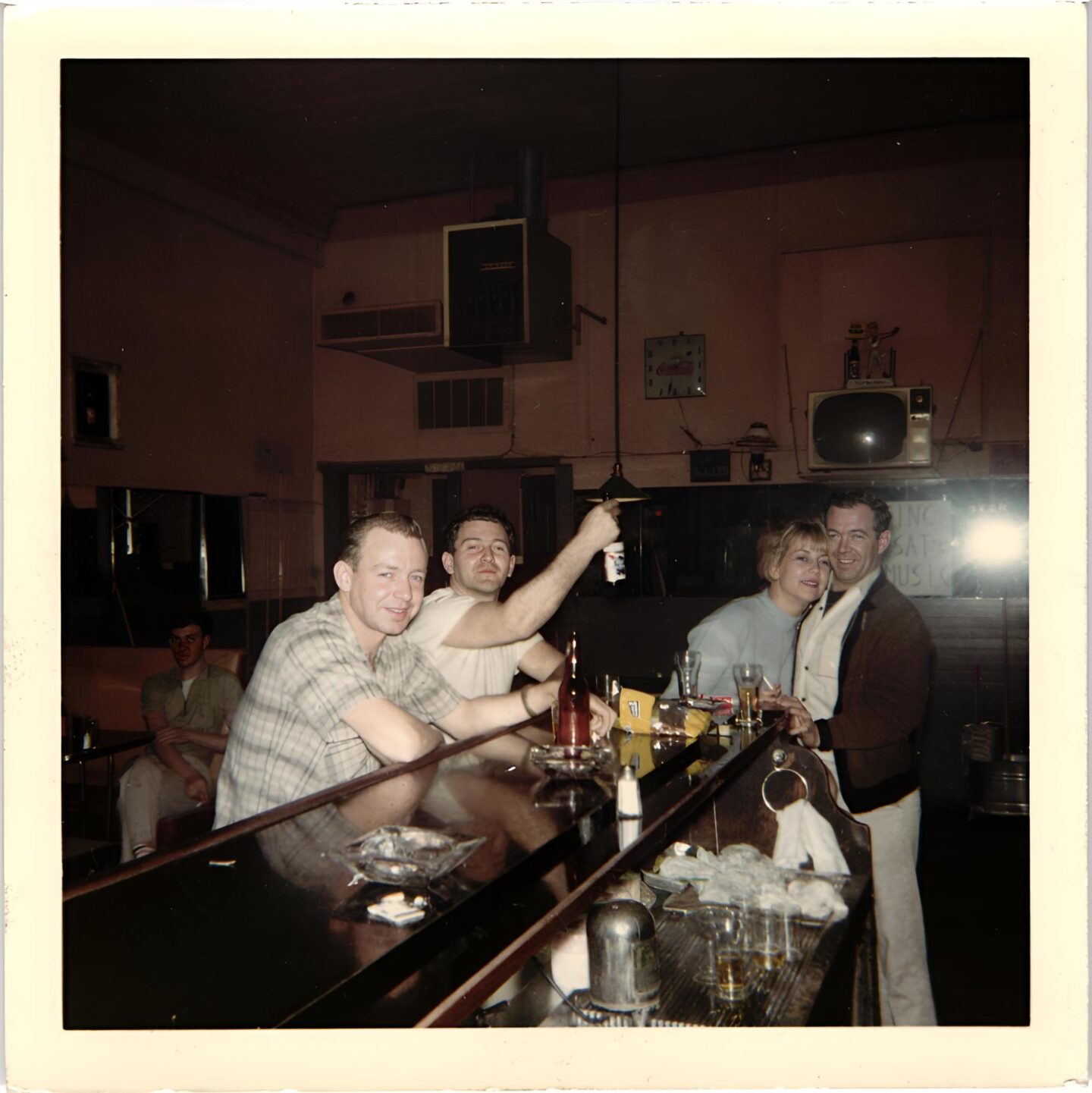 Women hugging a man with others at a bar